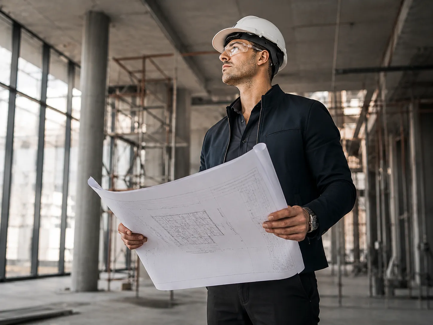 Construction worker holding blueprints in an unfinished building interior