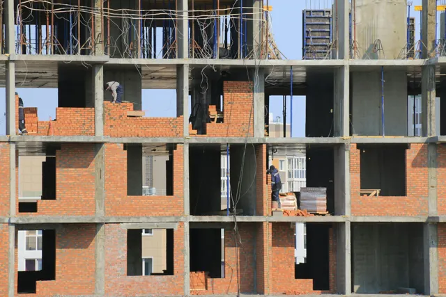 Partially built brick apartment building with exposed concrete floors and open window frames