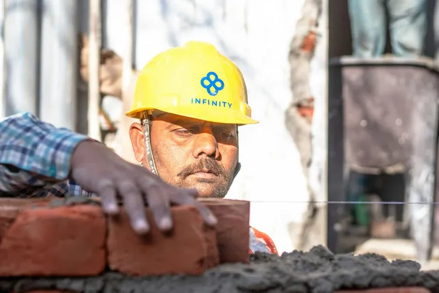 Construction worker in yellow hard hat stacking bricks at a job site