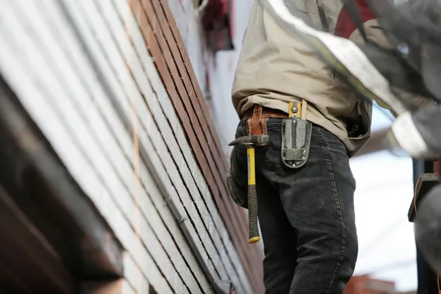 Construction worker with tool belt standing beside a building facade