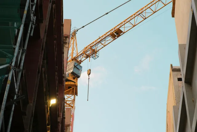 Construction crane between tall buildings against a blue sky
